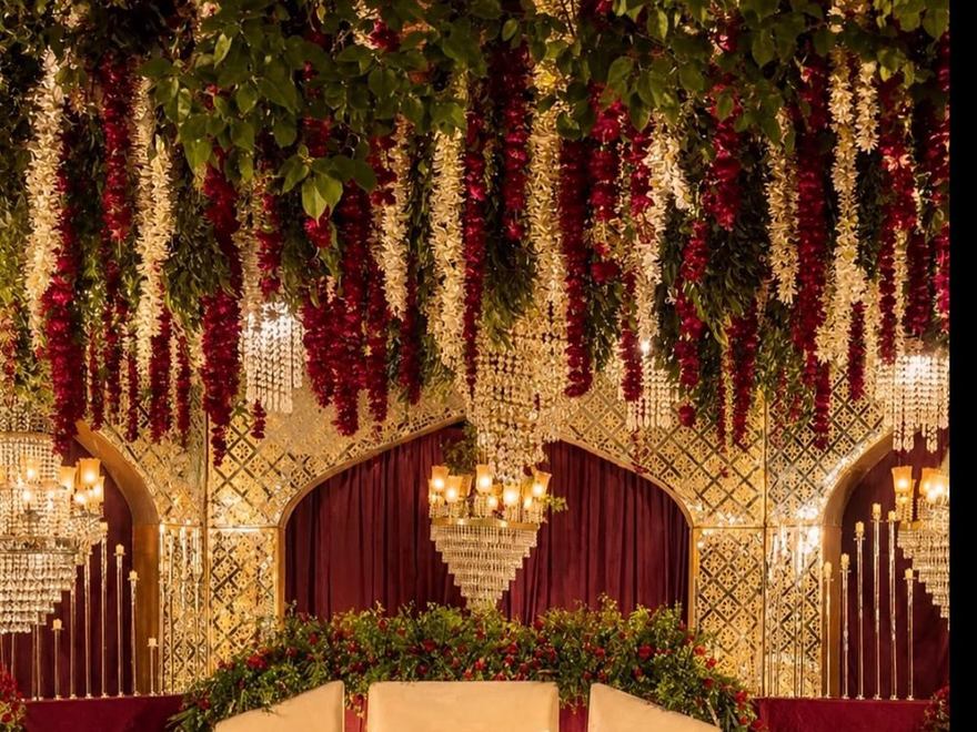 Walima stage in maroon and gold with hanging floral strings by Wedding Alley